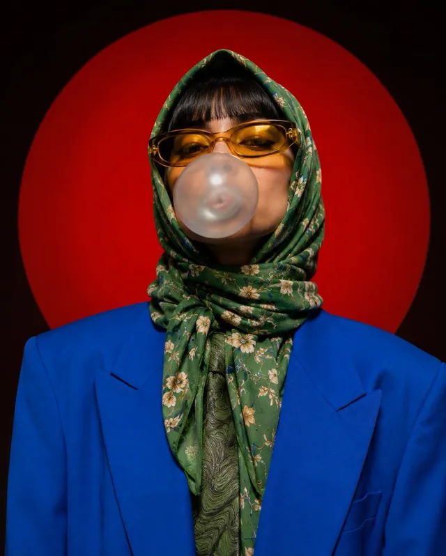 A stylized portrait photograph against a large red circul...