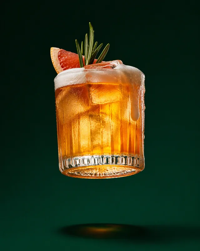 A premium [DRINK NAME] in a [GLASS TYPE] with [ICE / GARNISH / FOAM], suspended in midair against a clean [BACKGROUND COLOR] isolated backgr