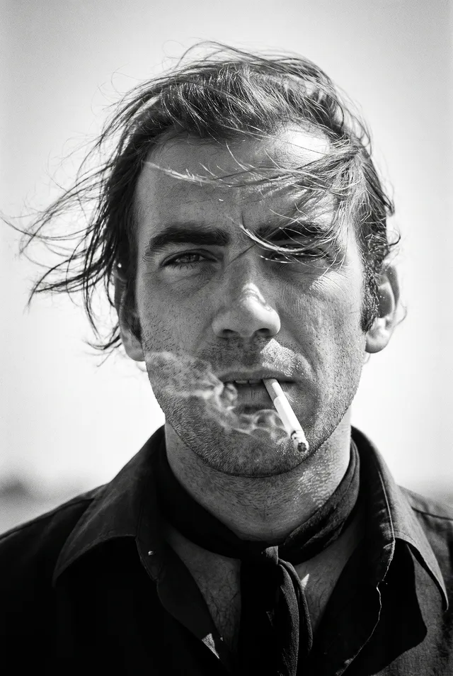 Create a 1970s black-and-white close-up portrait in a windswept outdoor setting, black and white noise.Camera/look: eye-level, fro