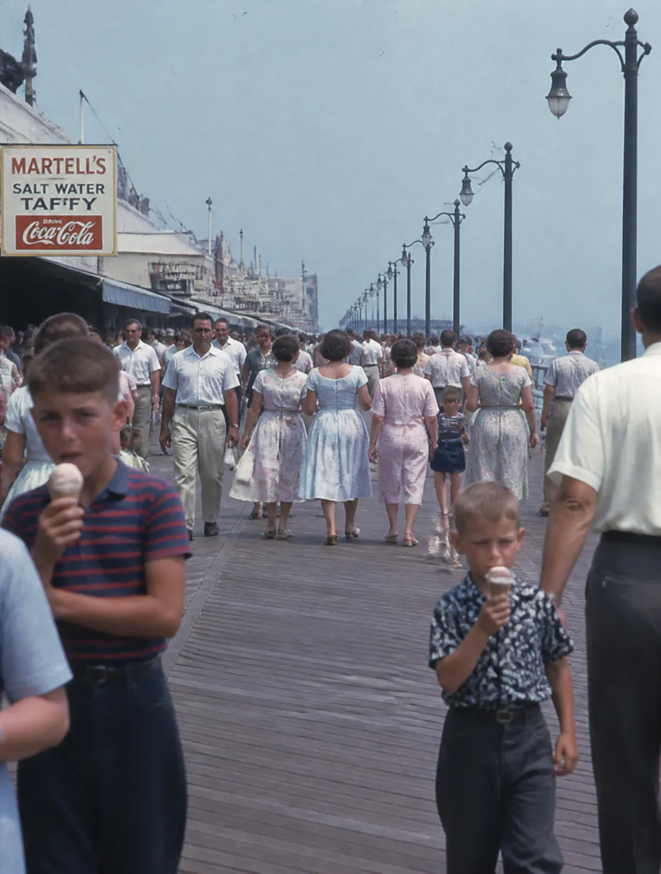پرامپت عکاسی با چت جی پی تی GPT Image : 1950s seaside boardwalk filled with families,… - ساخته‌شده با چت جی پی تی GPT Image